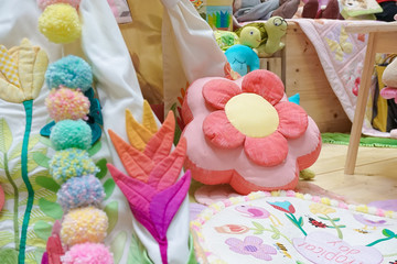 details of playroom for children with colorful decorations in spring concept and teepee tent. Selective focus on the pink flower pillow.