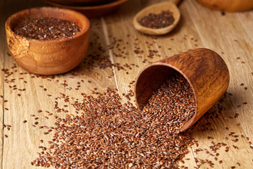 An overturned wooden bowl with linseeds on a rustic background, close-up, shallow depth of field, selective focus