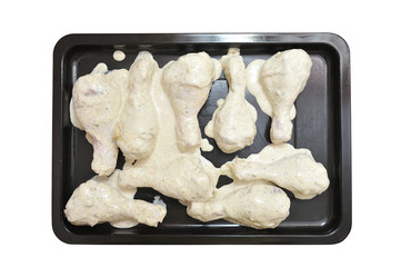 Cooking chicken legs. Chicken meat is laid on a baking sheet for baking in the oven. Isolated