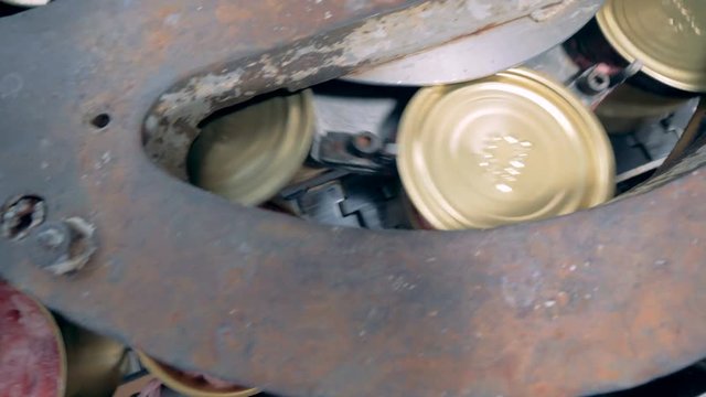 Top view of meat in tin cans going along the conveyor belt and getting closed