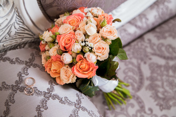 Wedding bouquet of orange and white roses with wedding rings