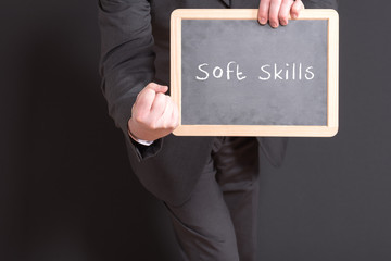 Soft Skills auf einer Tafel von einem Geschäftsmann gehalten mit einer geballten Faust