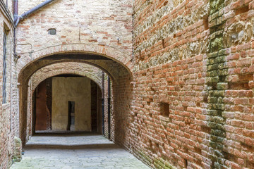 Old-fashioned alley with brick walls in an old village