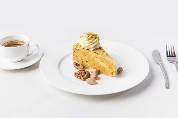 close up view of piece of cake with nuts and cup of coffee isolated on white surface