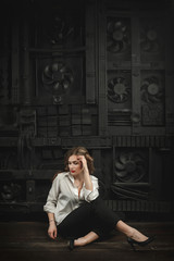 girl in a shirt on a background of a black mechanical wall
