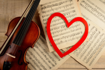 violin sheets with notes and a red heart on the table