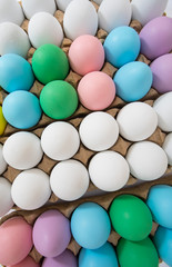 Colorful Easter eggs in egg crate, flat lay view on a wide angle