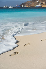 Ocean waves rolling to the foot prints on the tropical beach with azure water