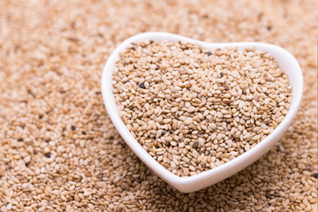 white sesame in wooden spoon on sesame background.