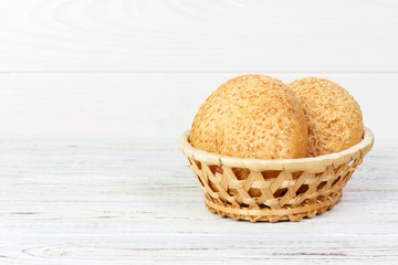 Tasty bun with basket bread on wooden background