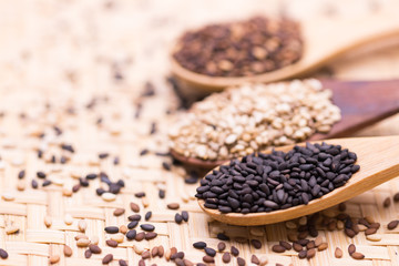 white sesame in wooden spoon on sesame background.
