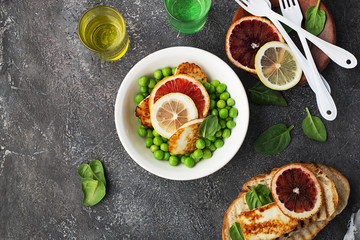 Green young peas, cheese haloumi, lemon. orange salad with slices of bread. Top View