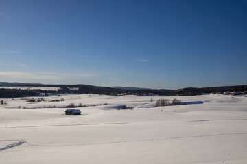 Snow covered field with some barns and a village in background