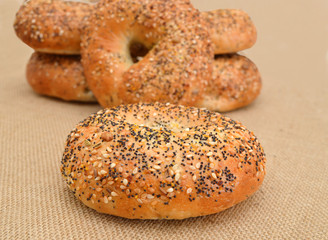 Closeup of a group of assorted bagels on a wood table top with burlap in the background