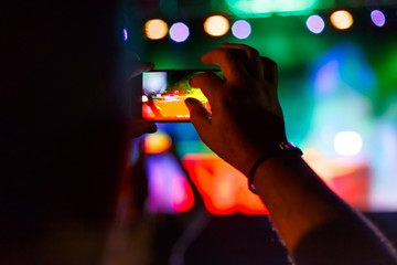 Fototapeta na wymiar Man capturing a video on a mobile phone at a music festival.