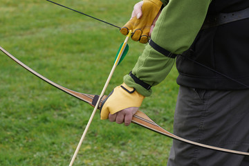 An archer nocking an arrow on to an American style laminated wooden flatbow