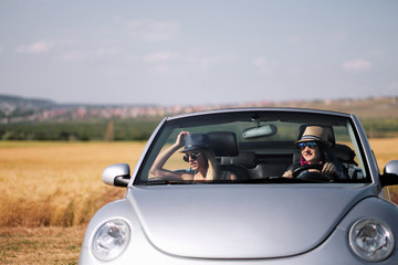 Fototapeta na wymiar Girl driving a convertible car in a summer poppy field