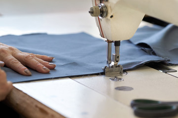 Closeup of an industrial sewing machine sews a ratchet strap.