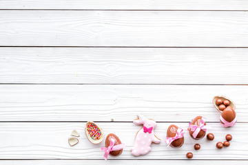 Celebrate Easter. Modern signs of Easter. Chocolate Easter eggs and Easter bunny cookies. White wooden background top view copy space