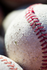 Basket of old baseballs and softballs on ground