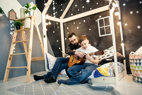 Man and boy in jeanses playing guitar