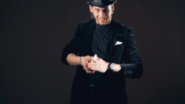 A male magician is performing a trick with a card deck