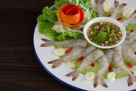 Shrimps chilled in fish sauce on white dish with vegetable and green spicy sauce Thai food..