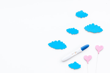 Positive pregnancy test near toy clouds and heart sign on white background top view copy space