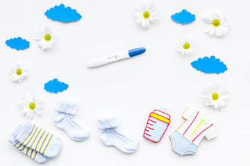 Pregnancy and preparation for childbirth. Pregnancy test near child accessories on white background top view