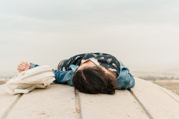 Concept of Freedom. Unidentified young woman in casual clothes with backpack rests on an unusual...
