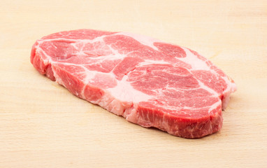 Raw pork neck meat cut isolated on wood background fresh one slice without bone .