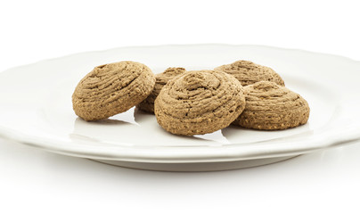 Cocoa oat cookies on a ceramic plate isolated on white background five drop shape brown crispy biscuits.