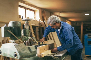 Naklejka na ściany i meble middle aged carpenter working in his workshop