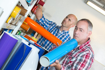 workmen examining rolls of coloured vinyl