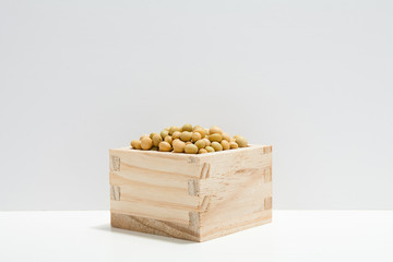 Soybeans in wooden bowl on white table 