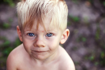 Portrait of a blond boy with blue eyes, a homeless child, a war child