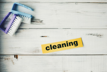 Cleaning house or office concept. Blue and purple cleaning brushes, Cleaning inscription on a white...