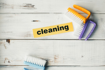 Cleaning house or office concept. Blue, yellow and purple cleaning brushes, Cleaning inscription on...