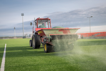 Pouring infill granules in to a football pitch with artificial grass.