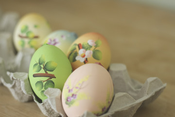 Easter egg hand painted craft decorated. Lying in egg carton. on rustic wood.  Shallow depth of field. Colourful.