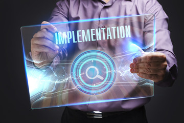 The concept of business, technology, the Internet and the network. A young entrepreneur working on a virtual screen of the future and sees the inscription: Implementation