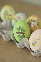 Easter egg hand painted craft decorated. Lying in egg carton. on rustic wood.  Shallow depth of field. Colourful.