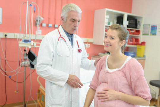 portrait of doctor examining and giving physiotherapy to pregnant woman