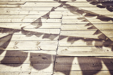 Shadows of Buddhist prayer flags on a wooden floor, color toned conceptual background.