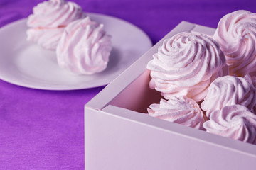Homemade marshmallows in a box and on a plate on a purple background. Toned