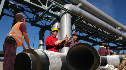 Industrial Workers at Work in Oil Refinery / Two engineers with group industrial workers doing oil refinery construction