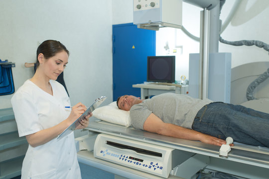 Patient on scanner bed, nurse making notes