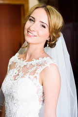 Gorgeous bride blonde in wedding dress posing at home and waiting for groom