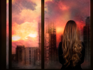 The girl looks through the window at the burning city