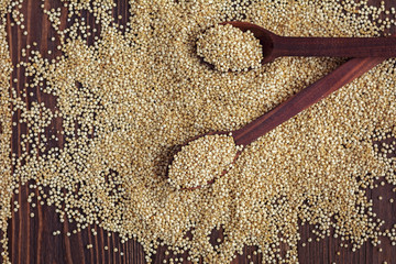 Kinoa seeds in wooden spoons on wooden table, flatlay